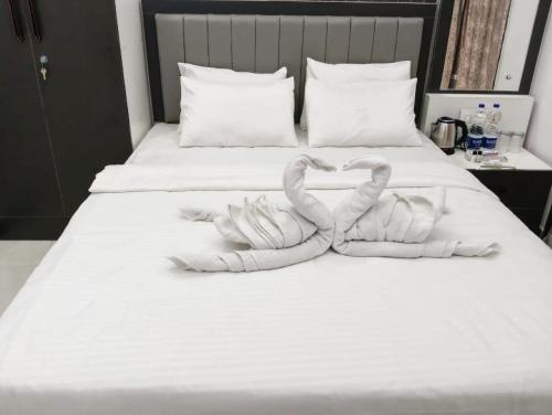 two towels shaped like swans sitting on a bed at Hotel Majestic Royal, Akkalkot in Akalkot