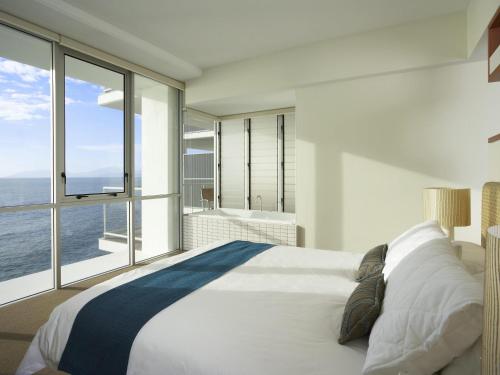 a bedroom with a large bed and a large window at Grand Mercure Apartments Magnetic Island in Nelly Bay
