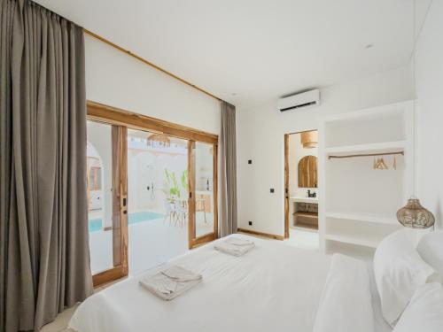 The Goya Lombok في كوتا لومبوك: غرفة نوم بيضاء مع سرير كبير ونافذة