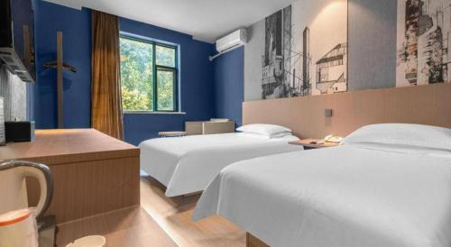 a hotel room with two beds and blue walls at Jinjiang Inn Wenzhou Shuangyu The Terminal in Jiangjunqiao
