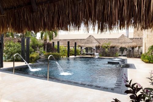 a swimming pool with a fountain in a resort at Dreams Puerto Morelos Resort & Spa - All Inclusive in Puerto Morelos
