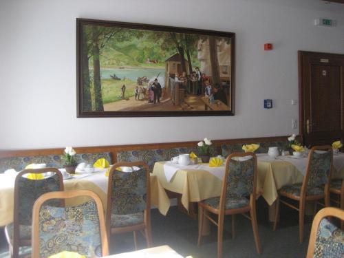 una sala da pranzo con tavoli e un dipinto sul muro di Hotel-Gasthof Maisberger a Neufahrn bei Freising