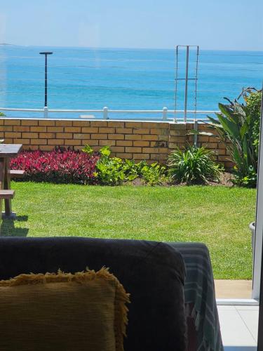 a couch in a yard with a view of the ocean at Bayview Seafront Apartment in Gonubie