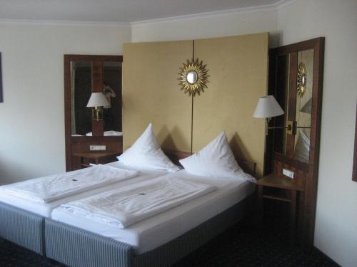 a bedroom with a bed with white sheets and a mirror at Hotel-Gasthof Maisberger in Neufahrn bei Freising