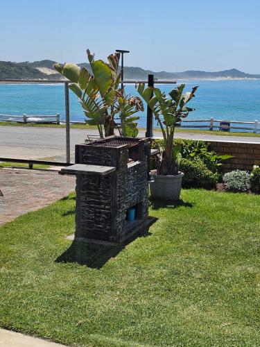 a stone bench sitting on the grass near the ocean at Bayview Seafront Apartment in Gonubie