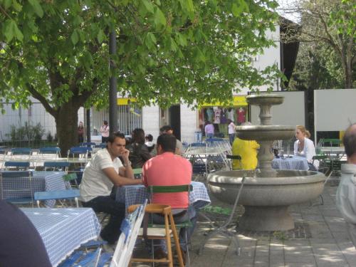 a group of people sitting at tables near a fountain at Hotel-Gasthof Maisberger in Neufahrn bei Freising