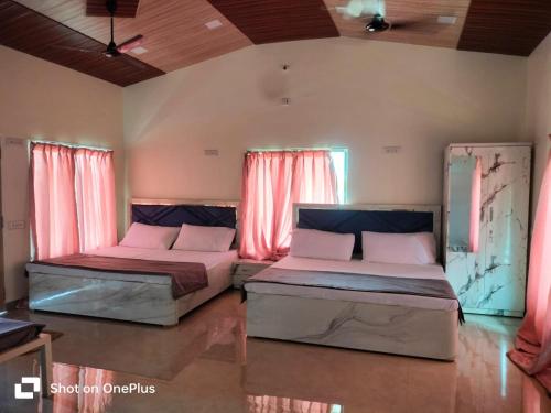 duas camas num quarto com cortinas cor-de-rosa em The Malshej Mist em Ghātghar