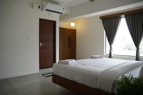 a bedroom with a large bed and a window at KK Service Suites in Coimbatore