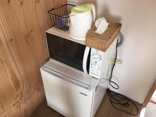 a refrigerator with a microwave on top of it at Shimanchu Guest House Yuien in Nanjo