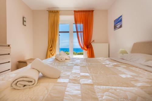 a large bed in a room with a large window at Villa Thea in Agios Nikolaos