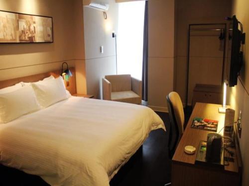 a hotel room with a bed and a desk and a bed sidx sidx at Jinjiang Inn Select Jiaxing Wanda Plaza in Jiaxing