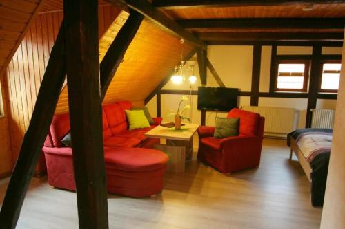 a living room with red chairs and a tv at Wohnung In Ilfeld Mit Grill in Harztor