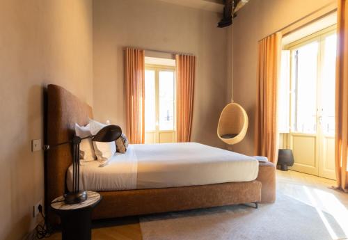 a bedroom with a bed with a lamp and windows at Palazzo Balsamo Boutique Hotel in Palermo