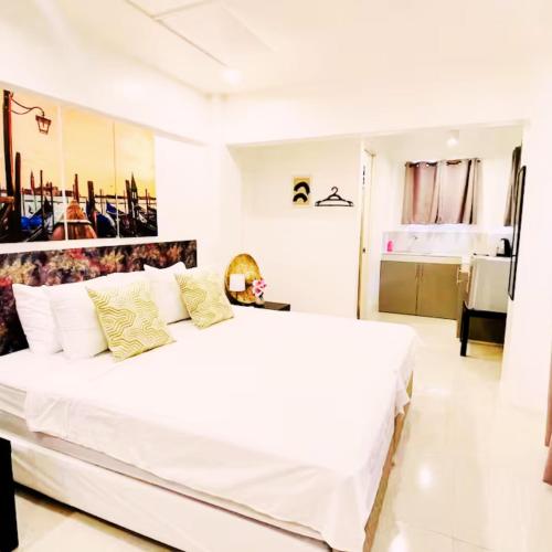 a white bedroom with a large white bed with yellow pillows at RiverCoves Resorts in Bulakan