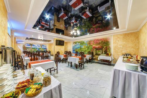 a restaurant with tables and chairs and a painting on the wall at Oscar Hotel in Gelendzhik