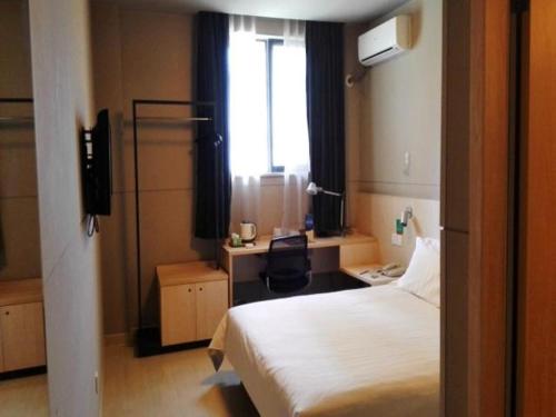 a bedroom with a bed and a desk and a window at Jinjiang Inn Xuzhou Golden Eagle International Shopping Center Jiahe East Street Hotel in Xuzhou