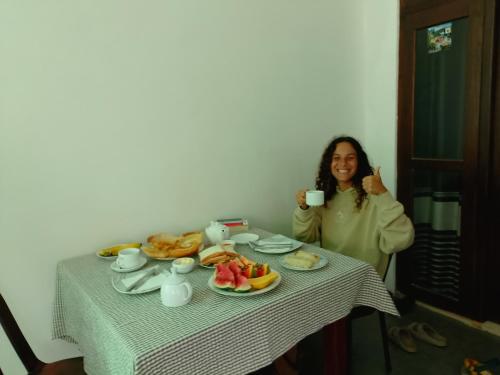 エッラにあるThe Canapy Nest Ellaの食べ物が置かれたテーブルの横でコーヒーカップを持っている女性