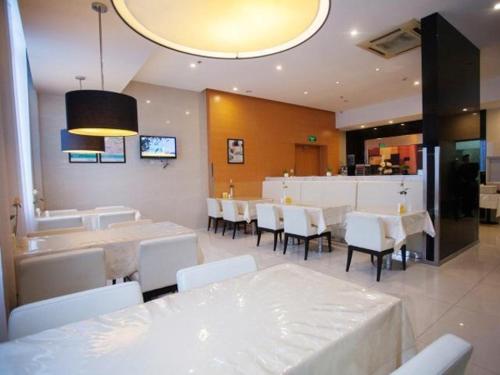 a restaurant with white tables and chairs and a kitchen at Jinjiang Inn Wuxi Central Station in Wuxi