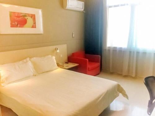 a bedroom with a white bed and a red chair at Jinjiang Inn Wuxi Central Station in Wuxi
