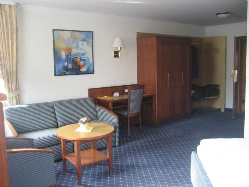 a hotel room with a couch and a table at Hotel-Gasthof Maisberger in Neufahrn bei Freising