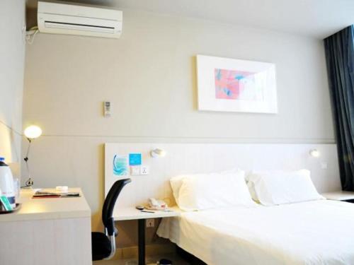 a hotel room with a bed and a desk with a computer at Jinjiang Inn Wujiang Zhongshan North Road in Suzhou