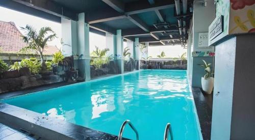 een groot blauw zwembad in een gebouw bij Grand Darmo Suite by AMITHYA in Surabaya