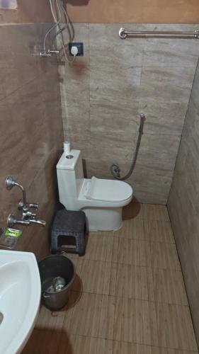 a bathroom with a white toilet and a sink at Buransh Retreat in Jageshwar