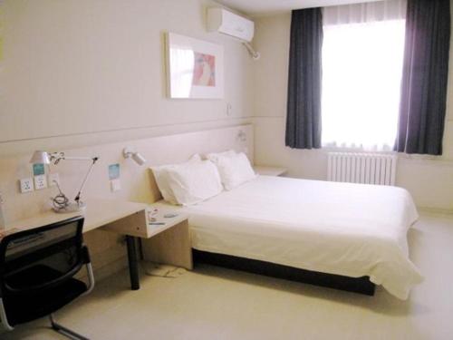 a bedroom with a bed and a desk with a computer at Jinjiang Inn Baoding Military School Square in Baoding