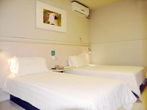 two beds in a hotel room with white sheets at Jinjiang Inn Baoding Military School Square in Baoding