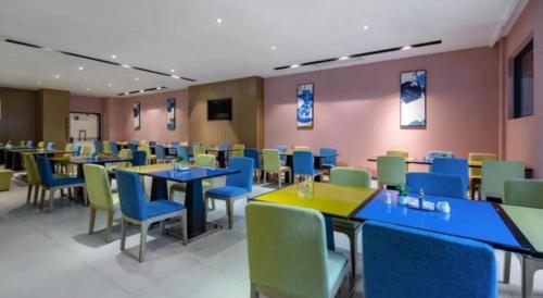 a dining room with tables and chairs in a cafeteria at Echarm Hotel Beihai Railway Station in Dianbailiao