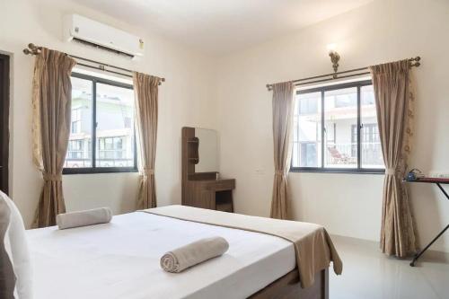 a white bedroom with a bed and two windows at 1bhk Premium BS1 - Candolim Calangute Area in Candolim