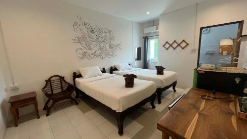 a room with two beds and a chair in it at OldTown Boutique House Sukhothai in Sukhothai