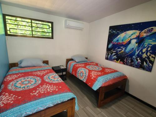 a bedroom with two beds and a painting on the wall at Pura Vida - Villa Elenita in Parrita