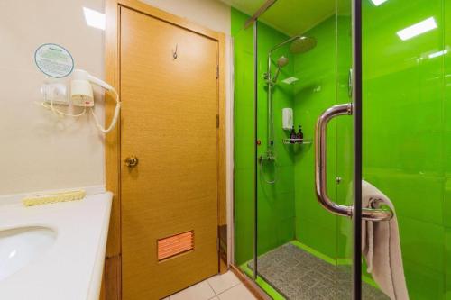a green bathroom with a shower and a sink at GreenTree Inn Tangshan Xueyuan Road Business Hotel in Fujiatun