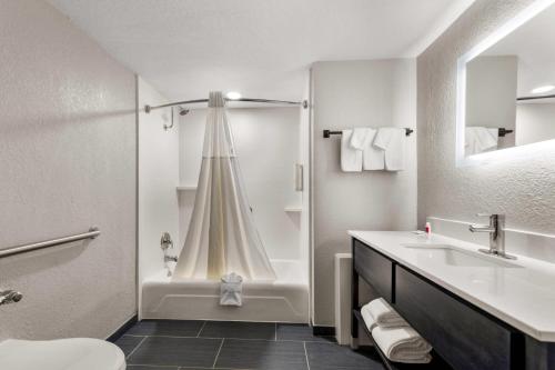 a white bathroom with a tub and a sink at Clarion Pointe Rhinelander Downtown in Rhinelander