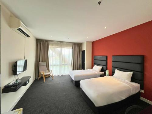 a hotel room with two beds and a flat screen tv at Estella Hotel in Pelabohan Klang