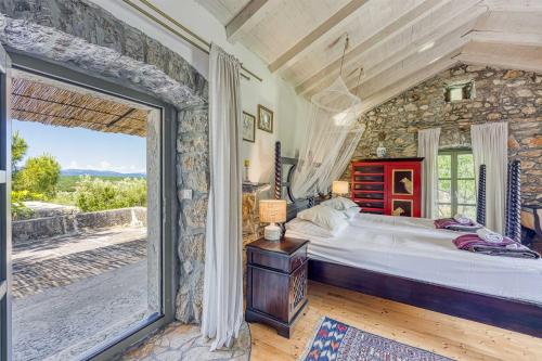 a bedroom with a large bed and a stone wall at Beautiful stone holiday house MENTA I in Bajčići