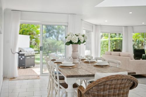 a dining room with a table with flowers on it at Beachfront Retreat - Ducted Air - Free Wifi in Coffs Harbour
