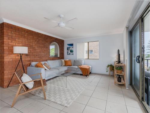 a living room with a couch and a brick wall at Layback on Marine in Kingscliff