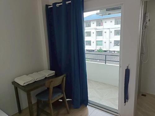 Una mesa y una silla en una habitación con ventana. en Comfy Hotels Suvarnabhumi Airport, en Samut Prakan