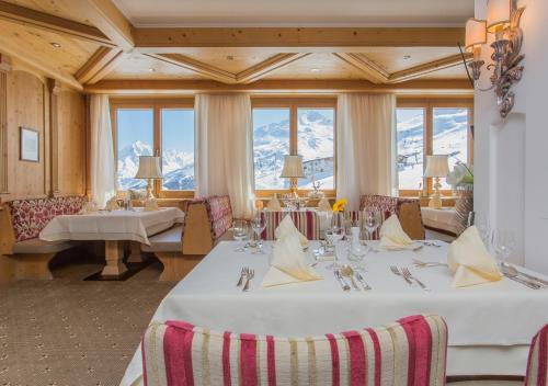 a dining room with a white table and some windows at Hotel Edelweiss Hochsölden Superior in Sölden