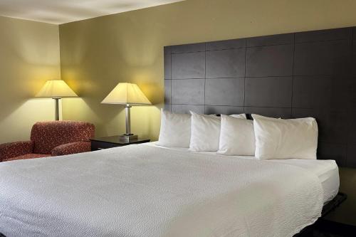 a hotel room with a large bed and a chair at Baymont by Wyndham Evansville North/Haubstadt in Haubstadt