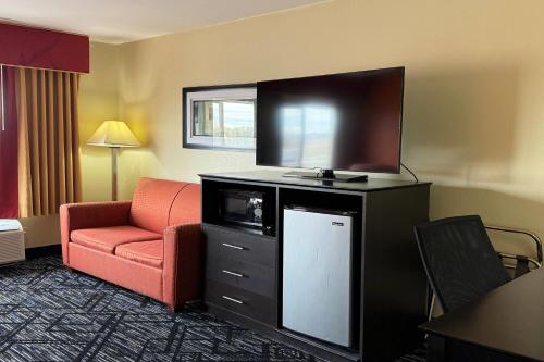 a hotel room with a tv and a red chair at Baymont by Wyndham Evansville North/Haubstadt in Haubstadt