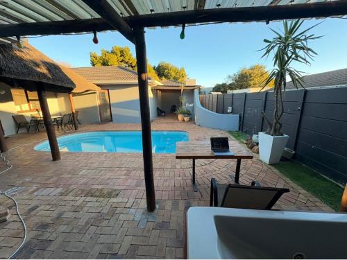 a patio with a pool and a table with a laptop on it at Joy House in Cape Town