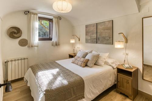 a bedroom with a bed with white sheets and a window at El Celler - Can Bonet in Sant Martí Vell