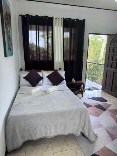 a bedroom with a large bed and a large window at Placido's Vacation Home in Puerto Galera