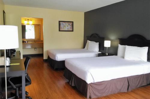 a hotel room with two beds and a desk at Econo Lodge Ormond Beach North - Daytona in Ormond Beach