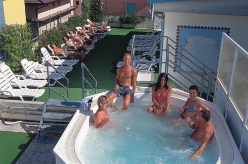 un groupe de personnes assises dans une piscine dans l'établissement Hotel Maxim, à Caorle