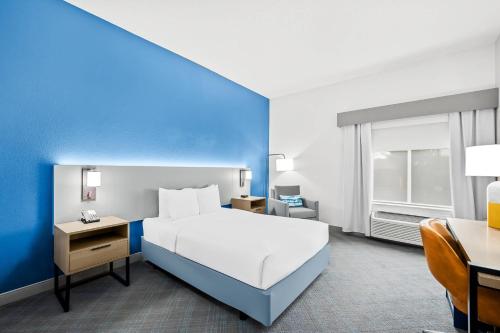 Un dormitorio con una cama blanca y una pared azul. en Comfort Inn Indianapolis East, en Indianápolis