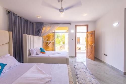 a bedroom with two beds and a door to a patio at Jamii Villas Diani in Kwale